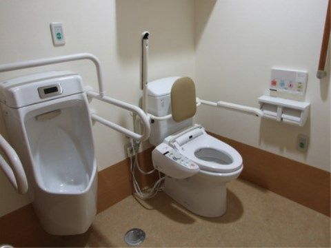 「ニチイケアセンター周南久米」の共用トイレ。可倒式の介助手すりを設置しており、スタッフサポートが行いやすい広い空間である。