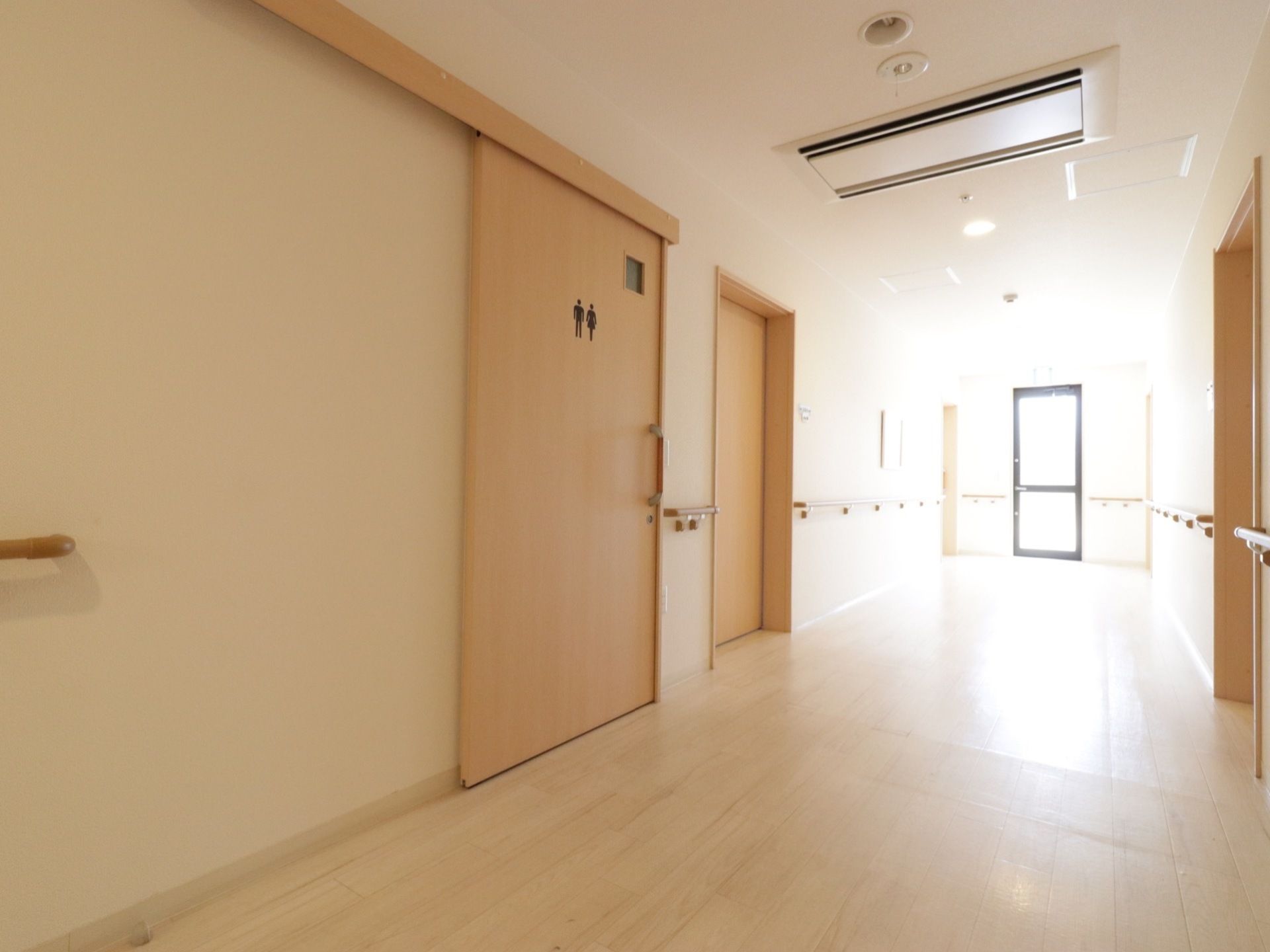 廊下の壁面にはドア以外の部分に手すりを配置している。大きく取られた窓から外光がたくさん入り、とても明るくなっている。