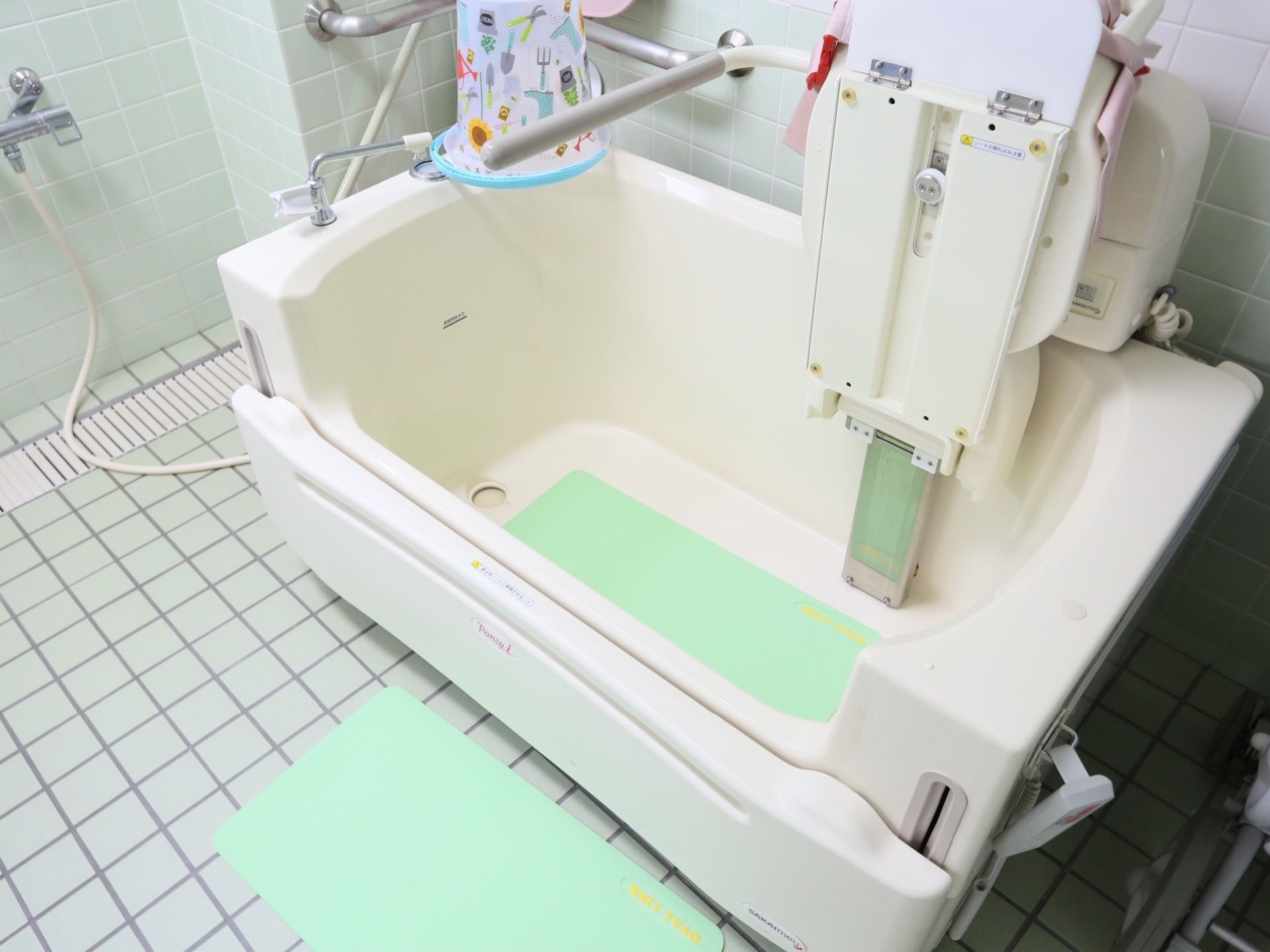 浴室に設置された介助用浴槽の前には淡い黄緑色の滑り止めのシートが敷かれており、入居者様は安全に入浴することができる。