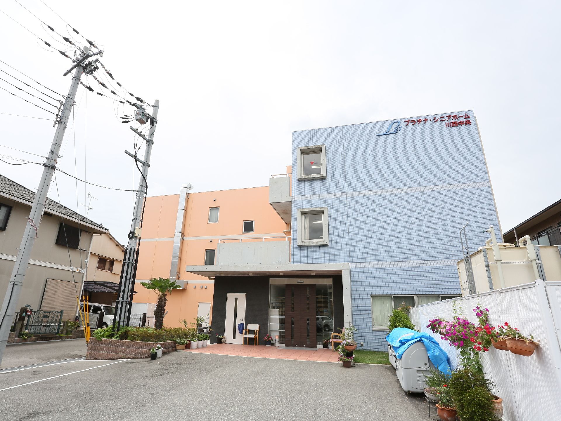玄関の自動扉のそばに椅子が置かれている３階建て施設の外観