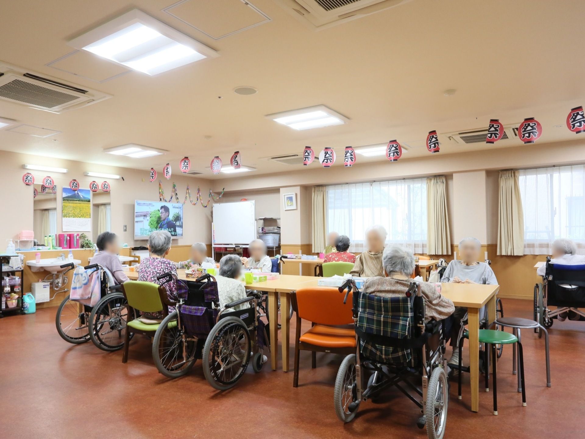 季節感を表現した共有スペースでは、用意されているテーブルセットに着かれている入居者様、皆さまの姿が見える。