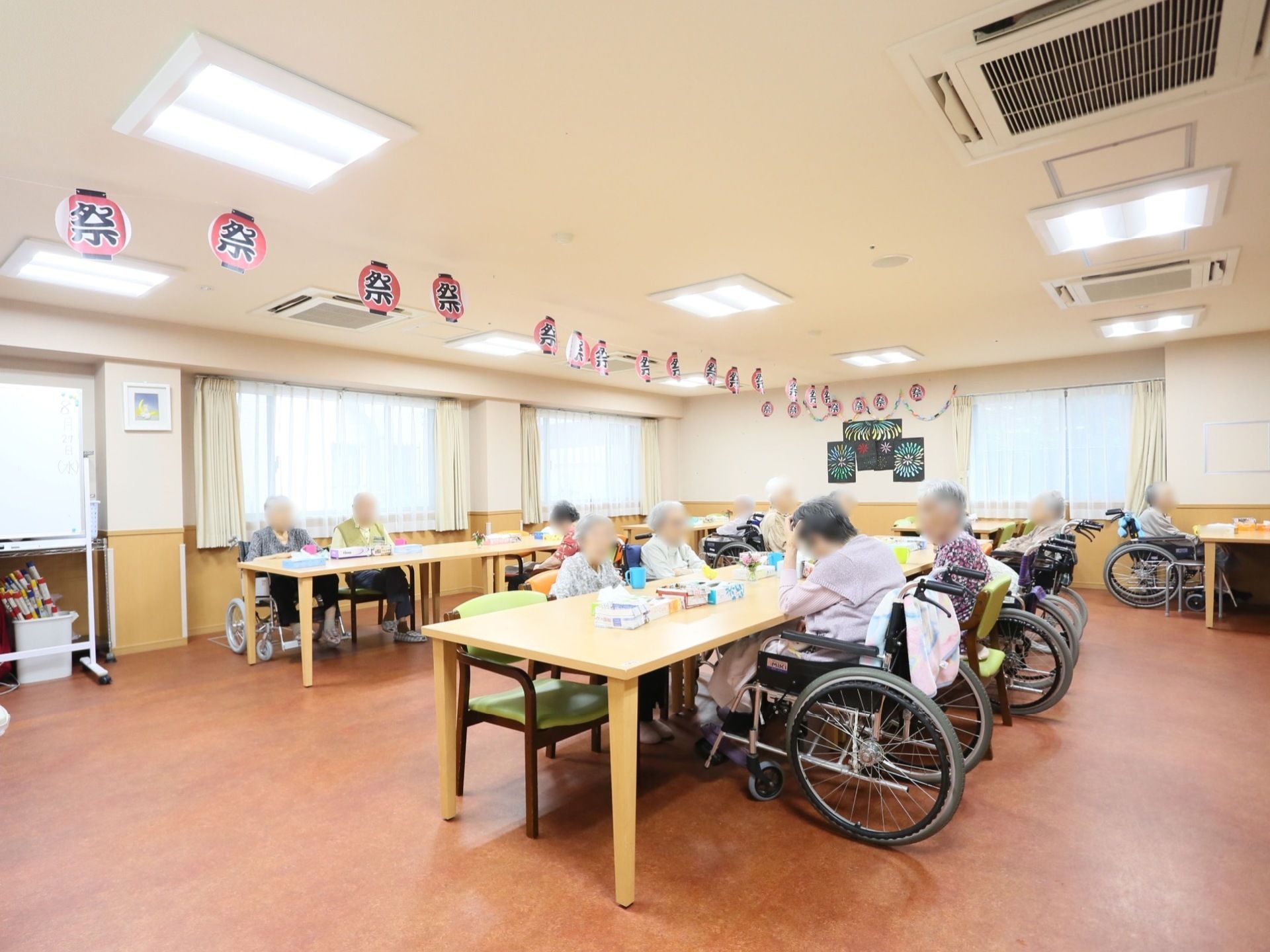 季節感を工夫してレイアウトされている共有スペースには、男女の入居者様、皆さまがテーブルに着かれている。