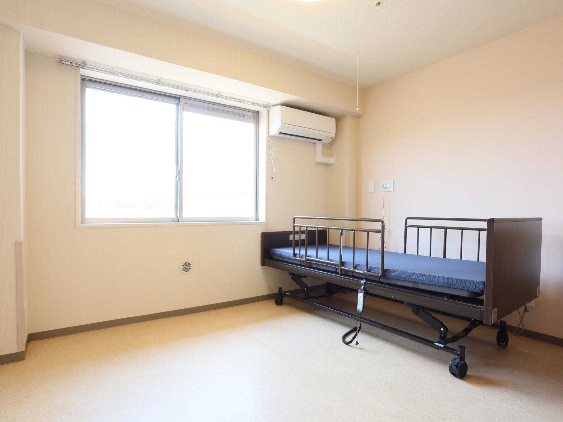 ご入居前の居室である。エアコンが完備された居室には窓から陽射しが入り、介護用ベッドが設置されている。