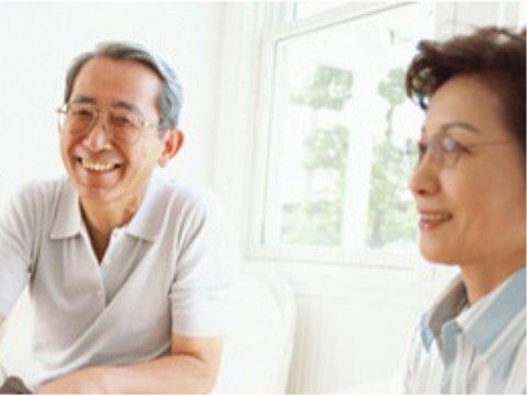 窓が付いている１室で微笑んでいる眼鏡スタイルの高齢の男性と女性