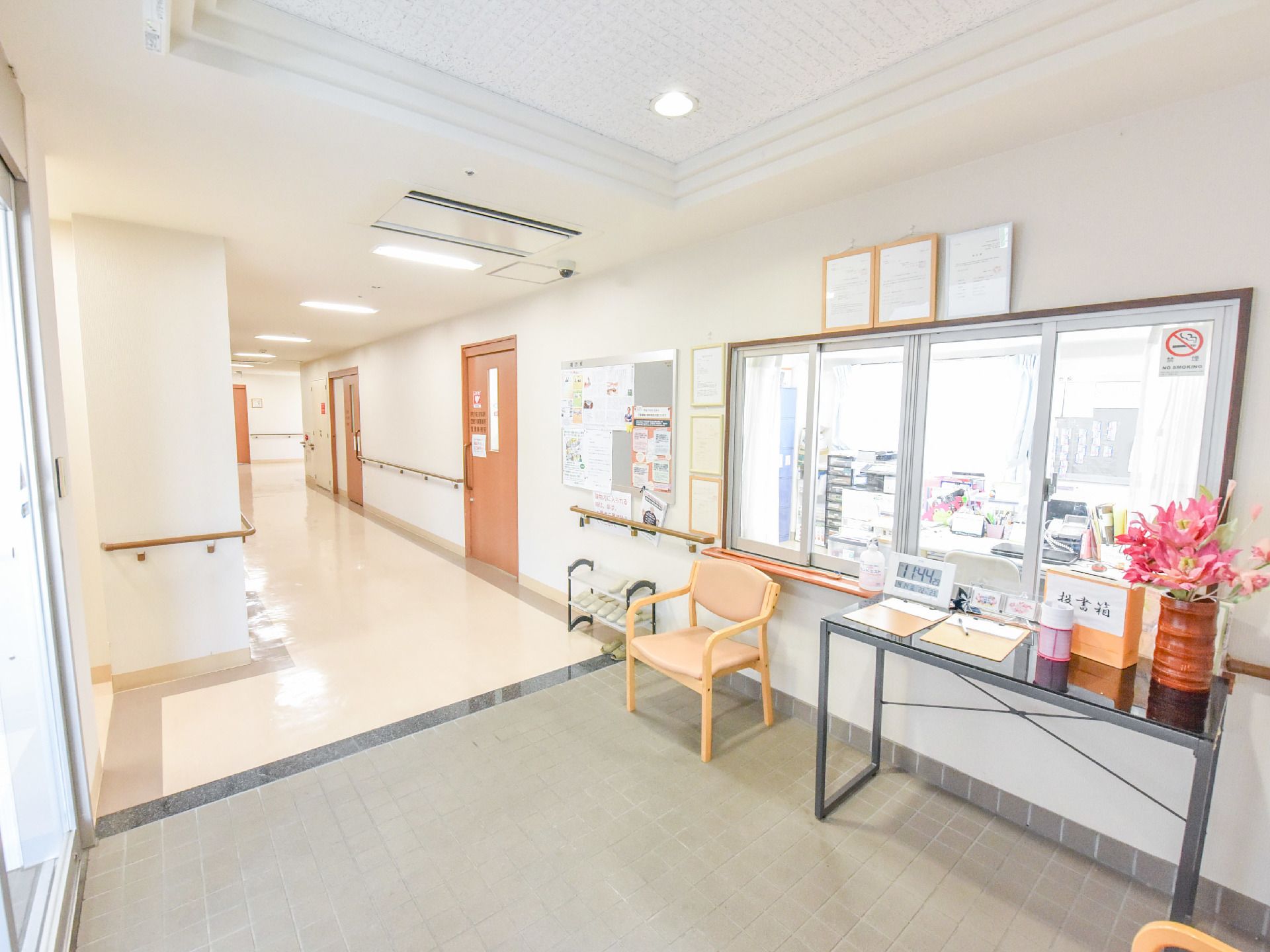 明るく広いエントランスホールである。正面にはガラス窓が付いた受付がある。受付の奥は事務所スペースになっている。