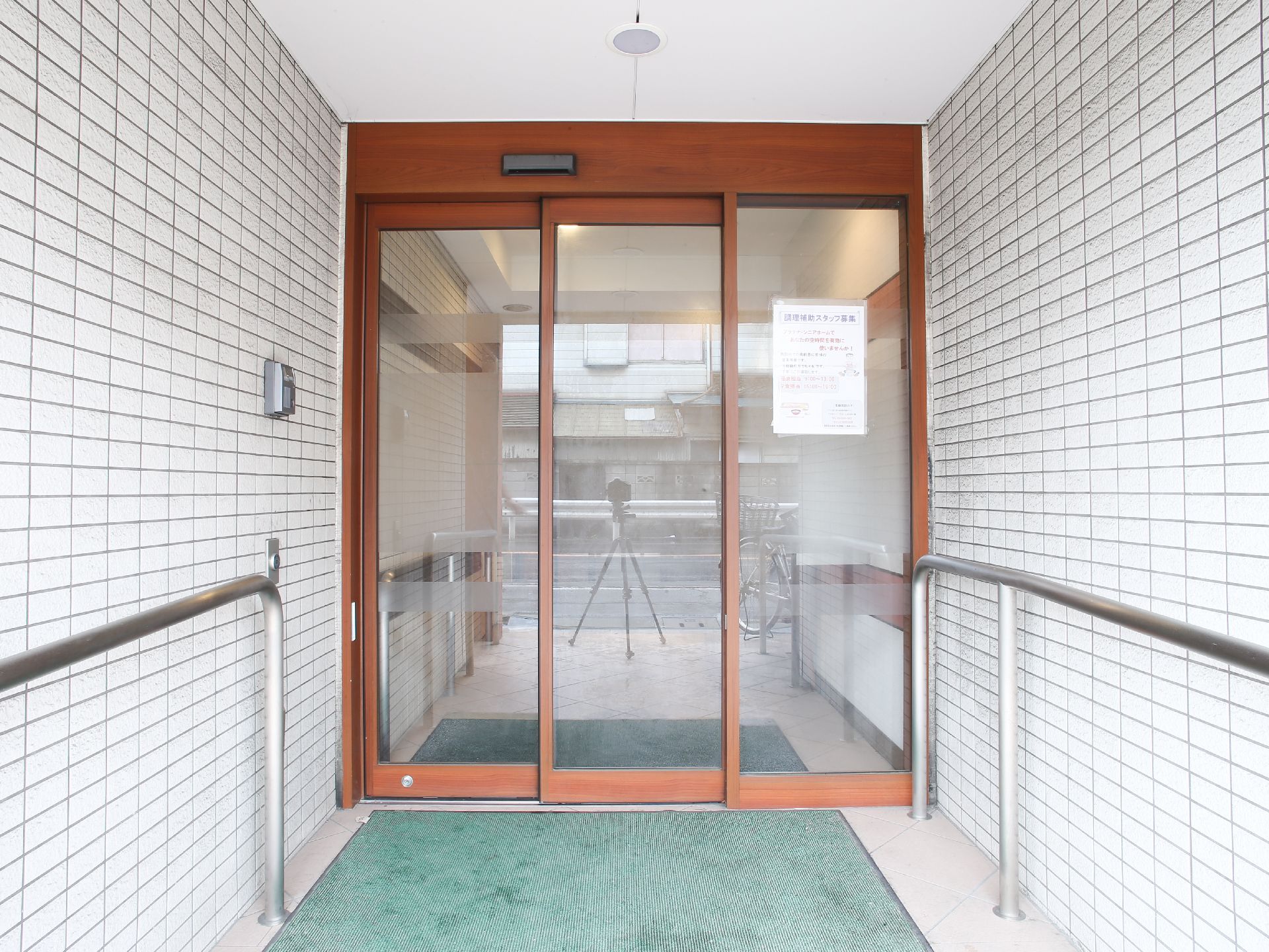 二重片引きの自動ドアになっている。自動ドア前には、滑り止め、汚れ落としの玄関マットがあったり、手すりがついている。