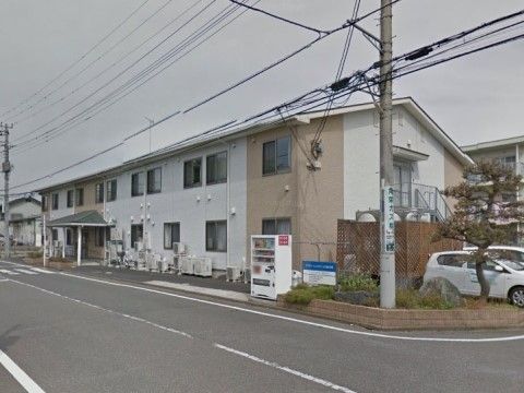 「プラチナ・シニアホーム川越的場」の外観。施設前に、自動販売機や植物が植えられた緑も豊かである。
