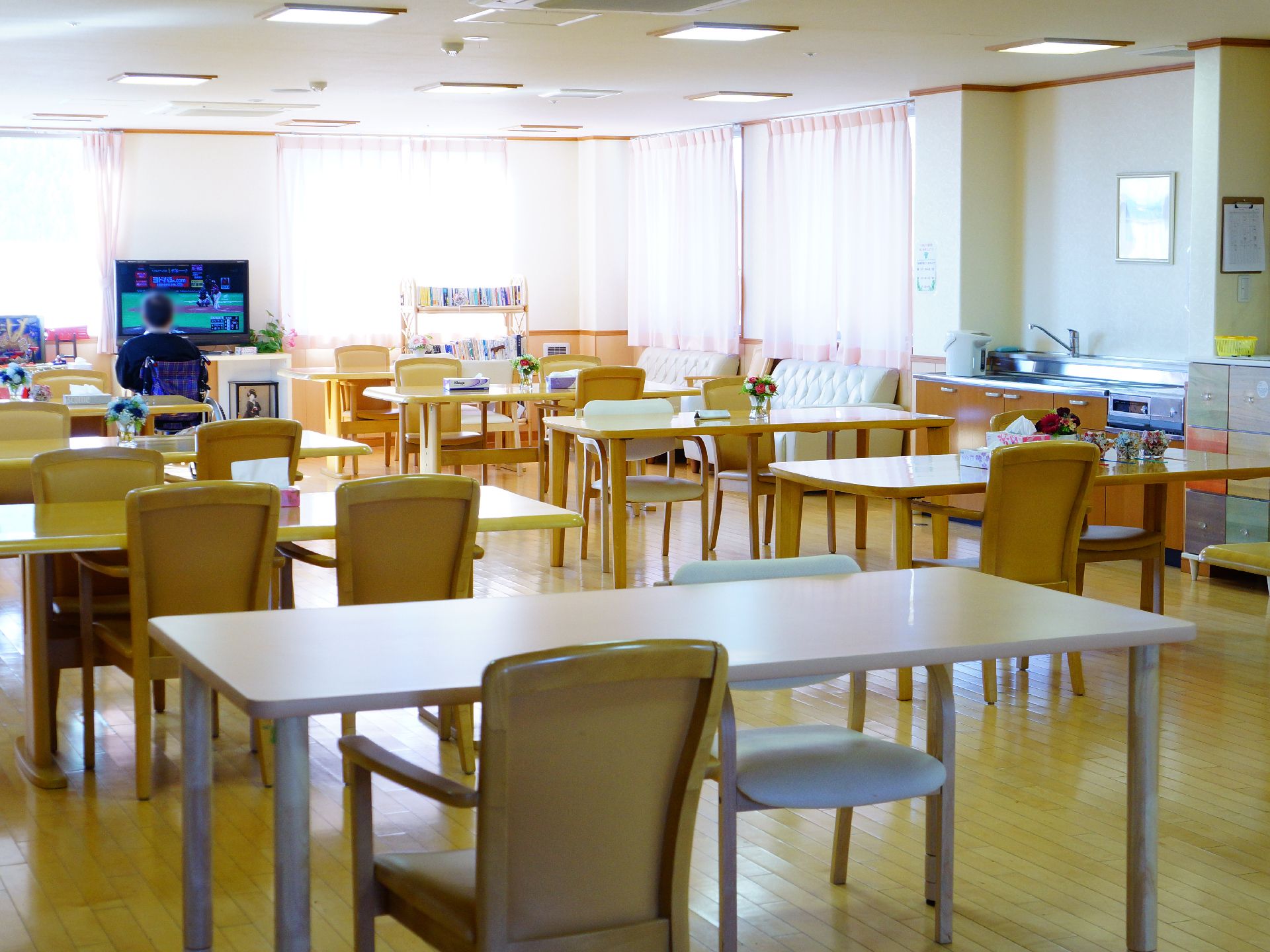 テーブルセットが配置され、テレビをご覧になっている男性の入居者様