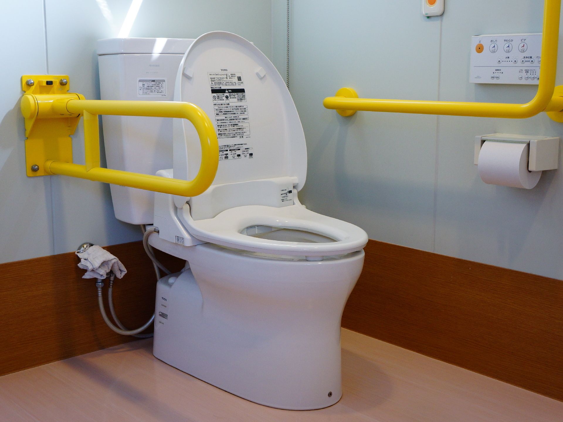 白色のトイレである。手すりは、立ち上がる時に安心である。ウォシュレットも付いているので、快適に使用できる。