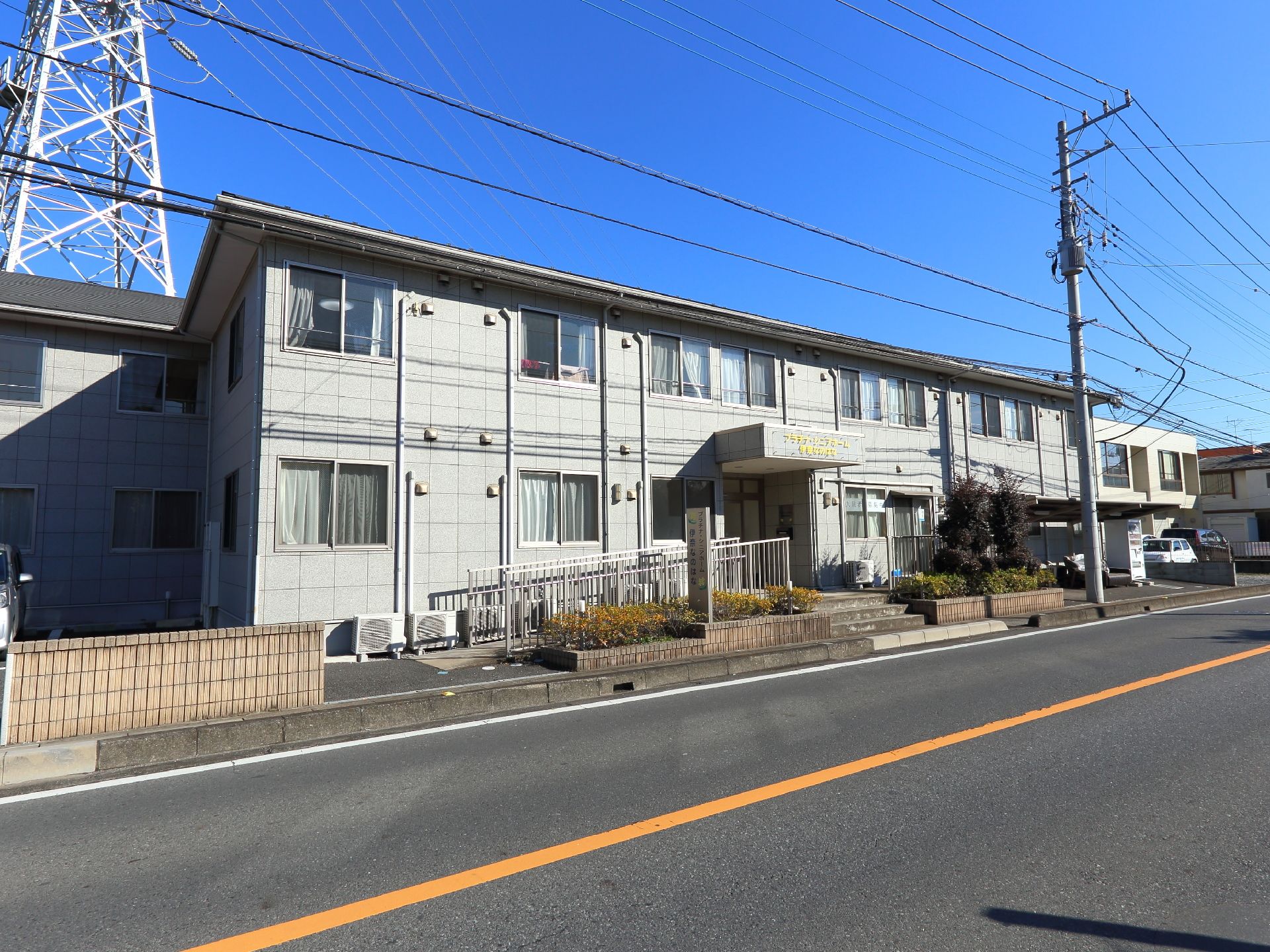 鉄骨造２階建ての施設である。建物の左側に駐車場が設けられている。手すり付きのスロープがエントランスに設置されている。
