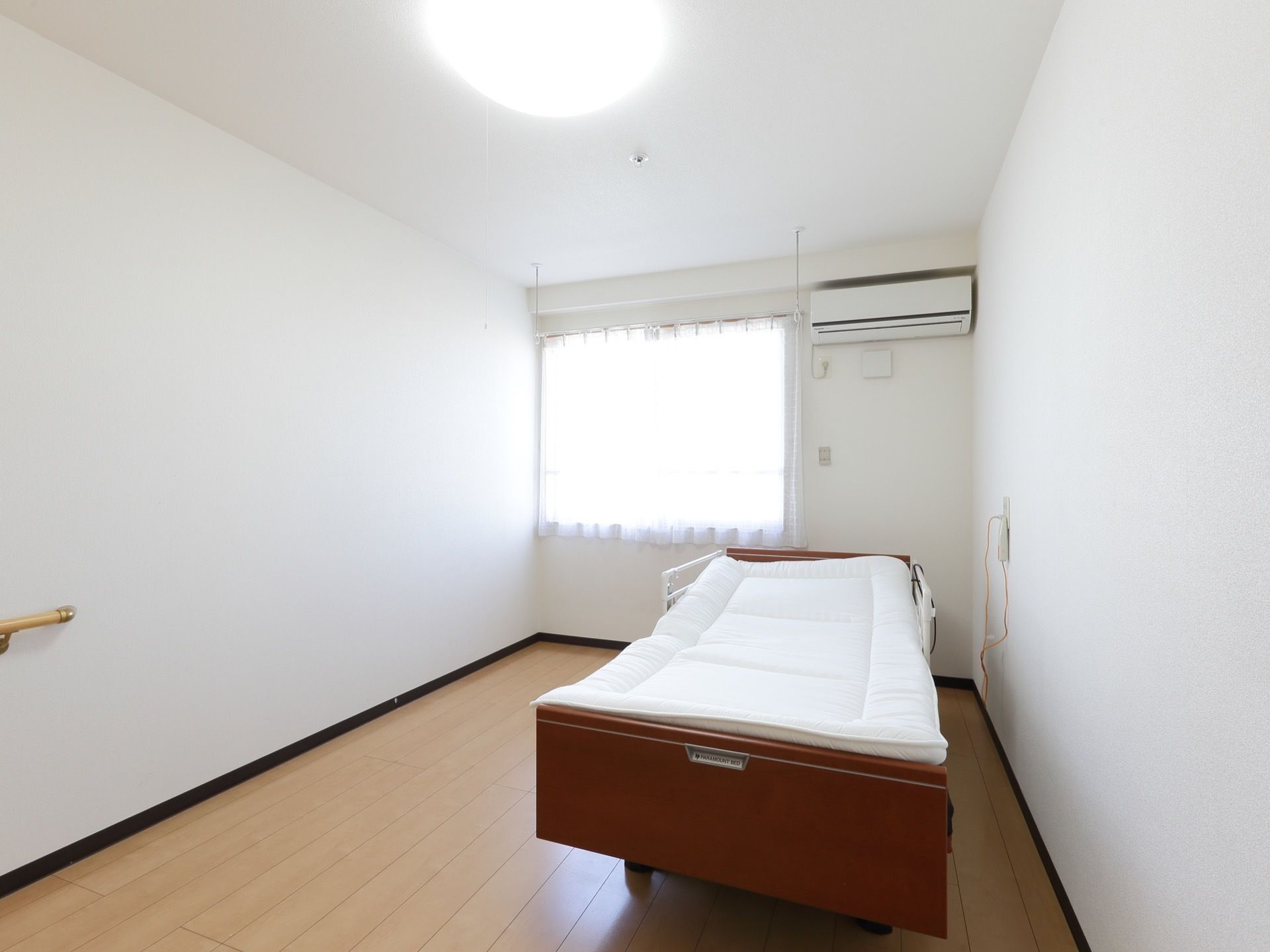 完全個室の居室には、介護ベッドが備わっている。壁には、転倒防止用の手すりやナースコール、エアコンが設置されている。