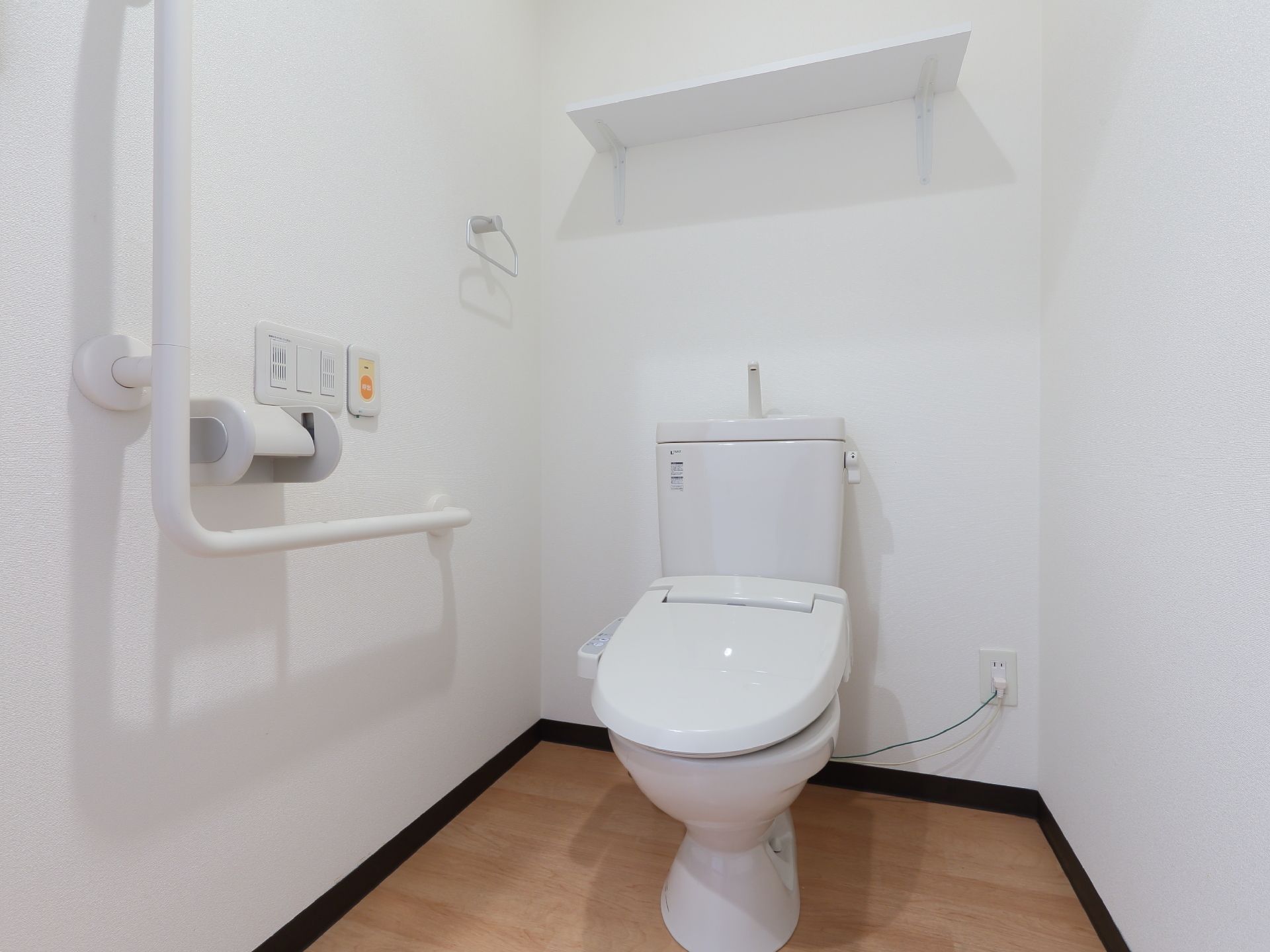 居室には、トイレを完備している。壁には、L型手すりや呼び出しボタン、備品を置ける棚が設置されている。