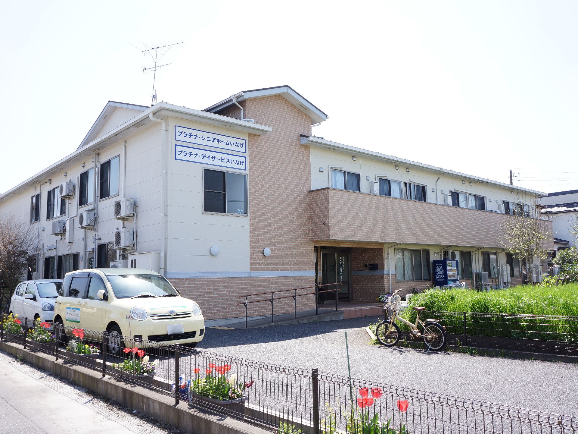 建物は、ベージュを基調とした2階建てになっている。敷地は広々としていて、車が通っても余裕のあるスペースがある。緑もたくさんある。