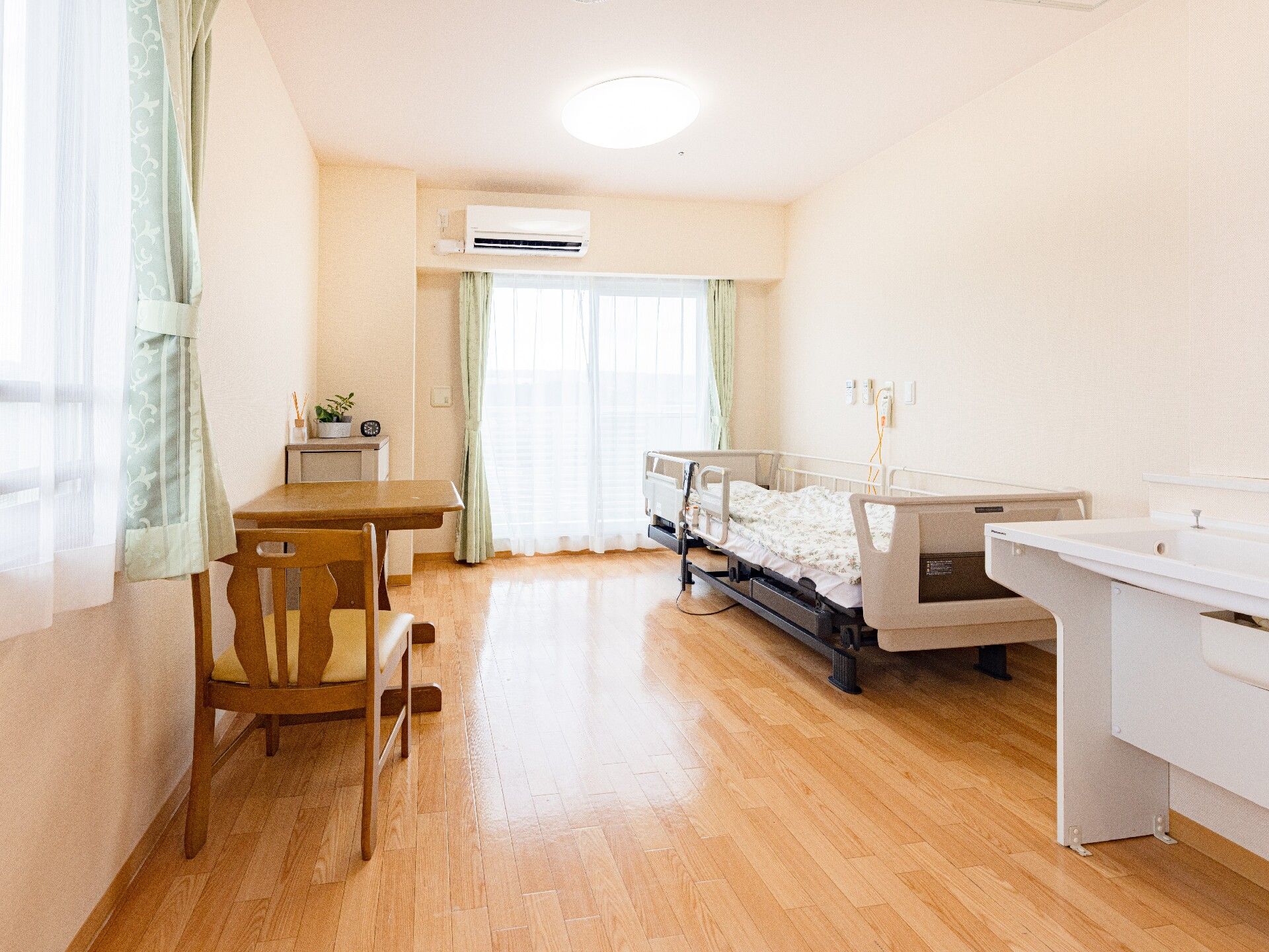 シンプルな作りの部屋。掃き出し窓は大きく、自然光が入り、外の景色も見ることができる。電動ベッドやナースコールが備え付けられている。