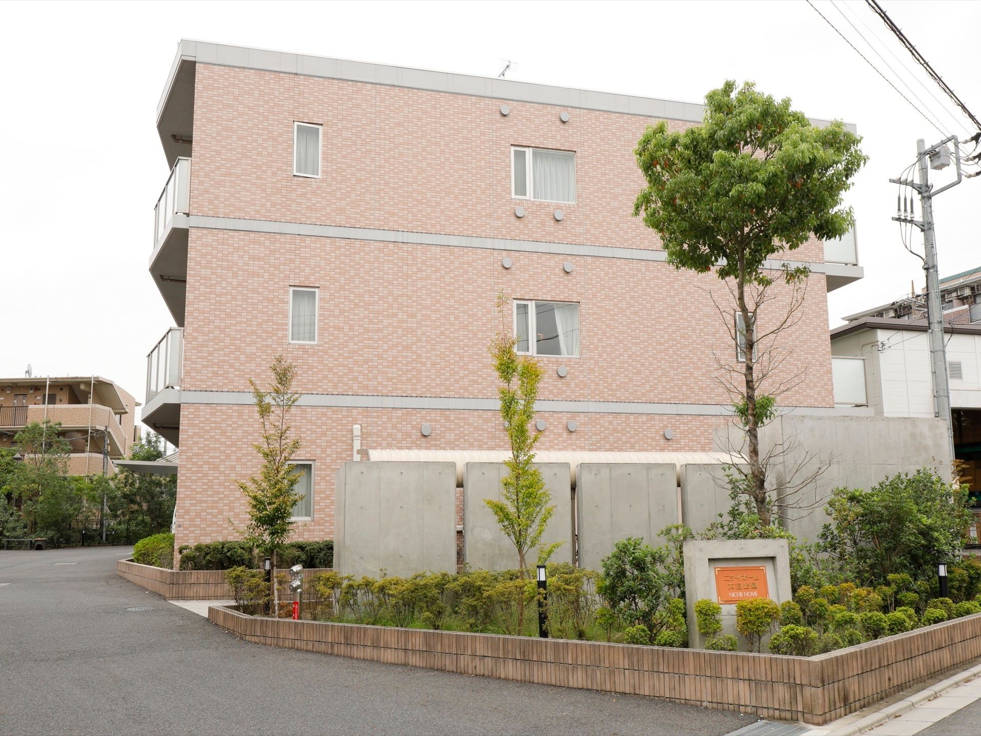 住宅街に位置している。敷地の出入り口には、施設名の記された看板が設置されている。木が植えられ緑豊かである。