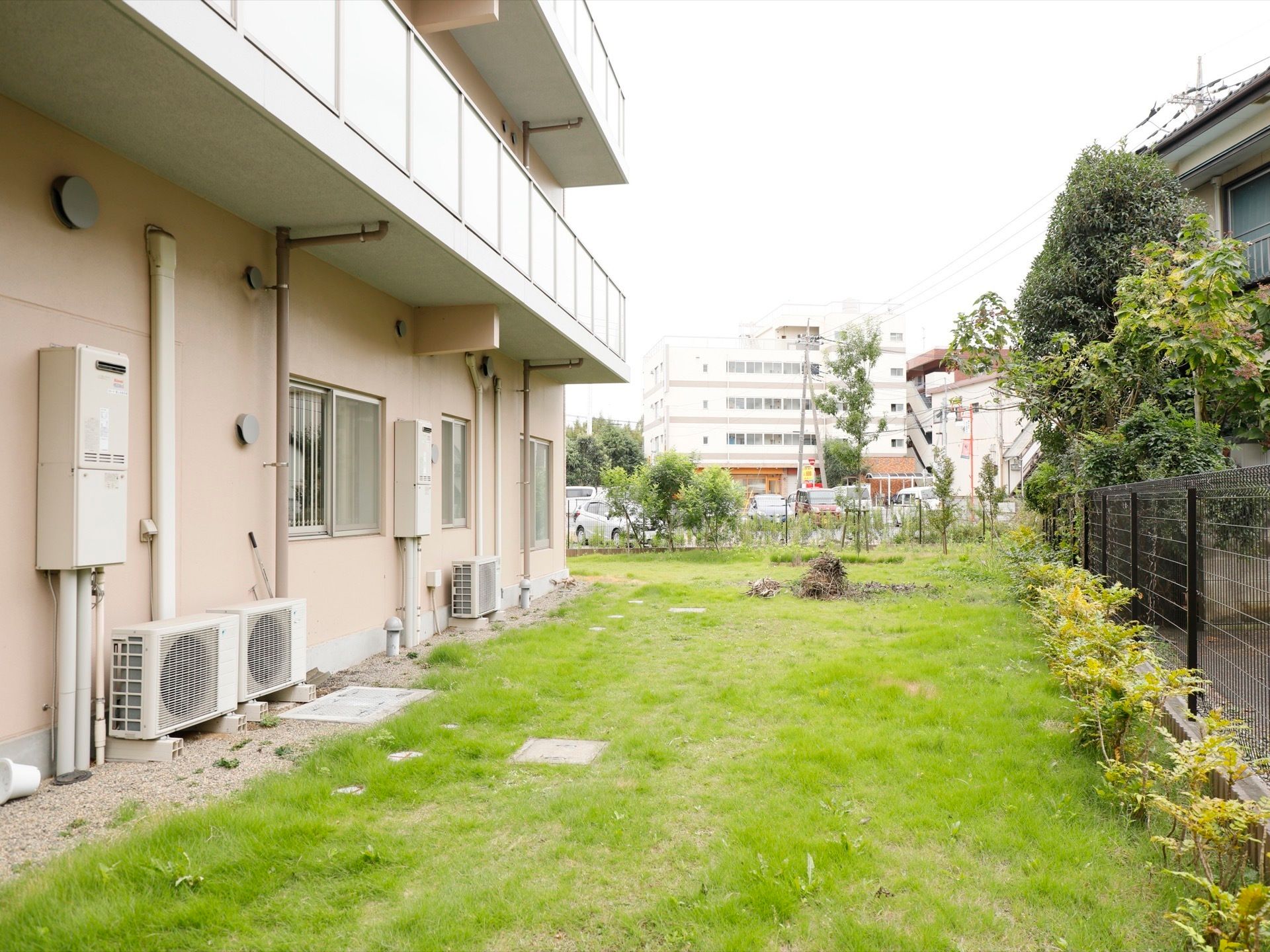 建物の裏は芝生が敷かれた庭になっている。敷地内はフェンスで囲まれており、庭木などの植物が植えられている。