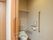 温水洗浄便座付きのトイレが設置されており、壁には手すりが設けられている。収納棚があり、小物などを整理できる。