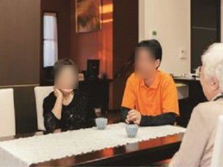 オレンジ色の制服を着たスタッフと談笑する高齢者2人