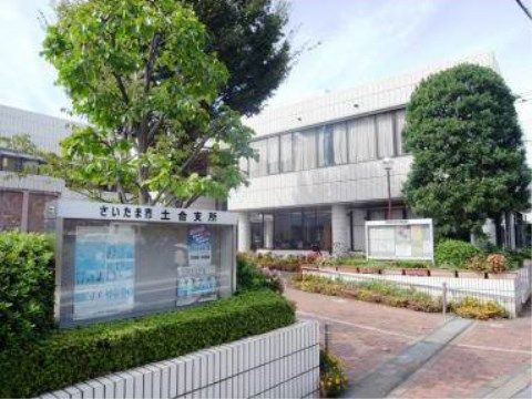 敷地入口には掲示板がある。建物は白のタイル張り、地面はレンガ色の石畳となっている。木や植物が多く植えられている。