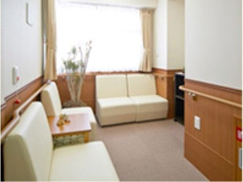 壁に沿って白い一人掛けのソファが用意されている。部屋の隅には観葉植物が置いてある。壁に沿って手すりが設置されている。