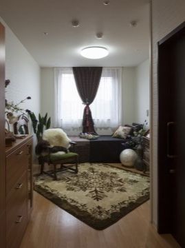 白い壁に茶色のフローリングの個室。重厚感のある家具やカーベットが配置されている。窓からは明るい陽が差し込んでいる。