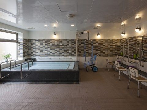 白い壁に、茶色を基調としたタイルが敷かれた大浴場である。壁にも浴槽にも手すりが完備され、洗い場にはシャワーチェアもあり、安全に入浴できる。