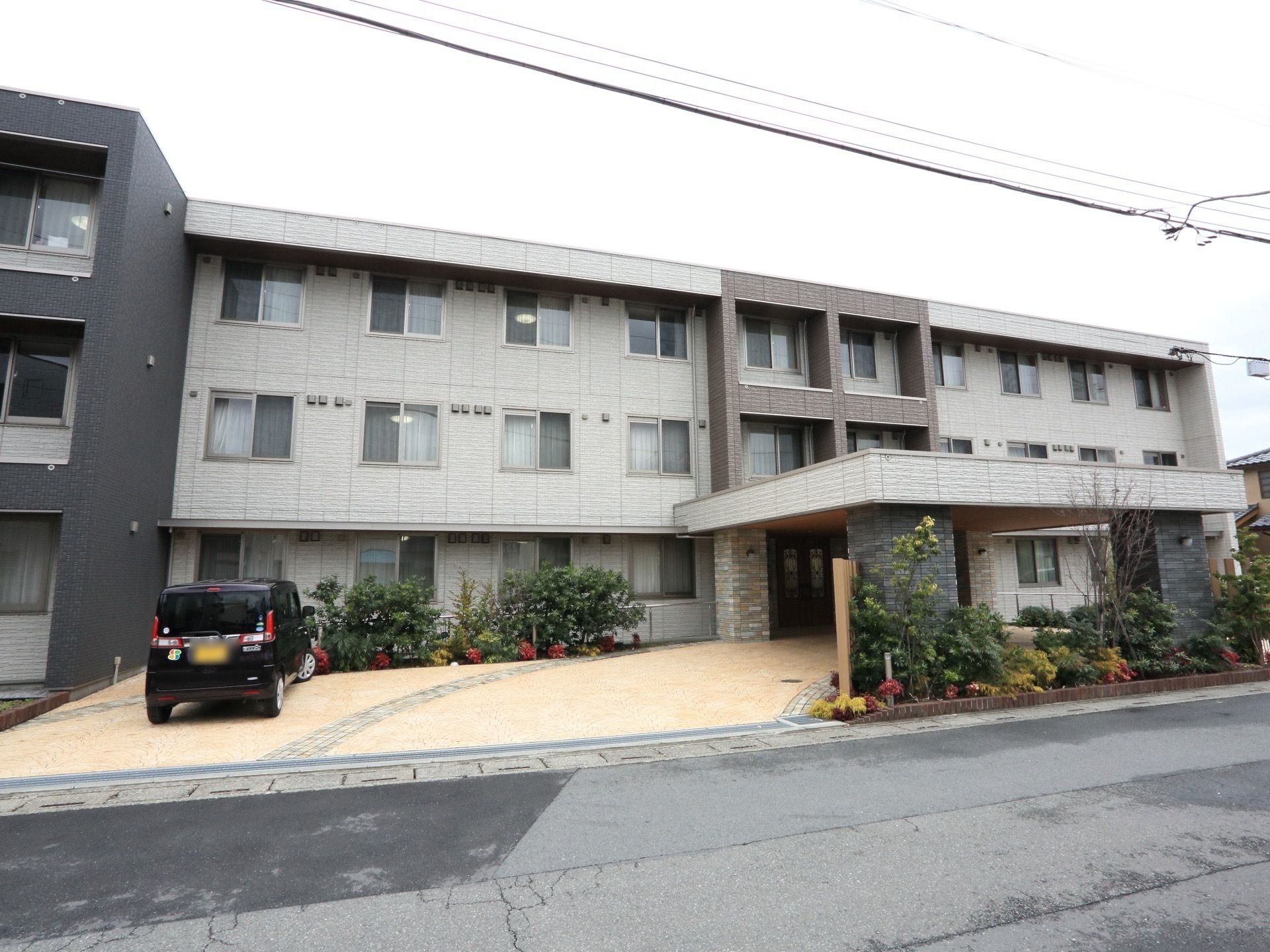 施設はグレーを基調とした３階建てのアパートのような外観。道路から施設内までバリアフリーになっている。