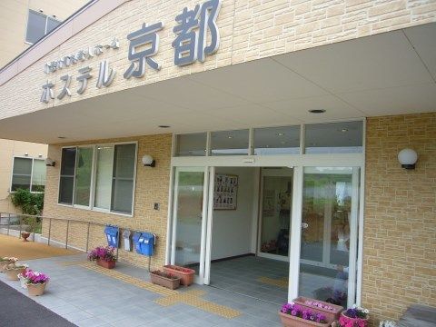 ホステル京都の外観。大きなエントランスルーフに落ち着いた茶色の外壁がおしゃれな施設外観となっております。