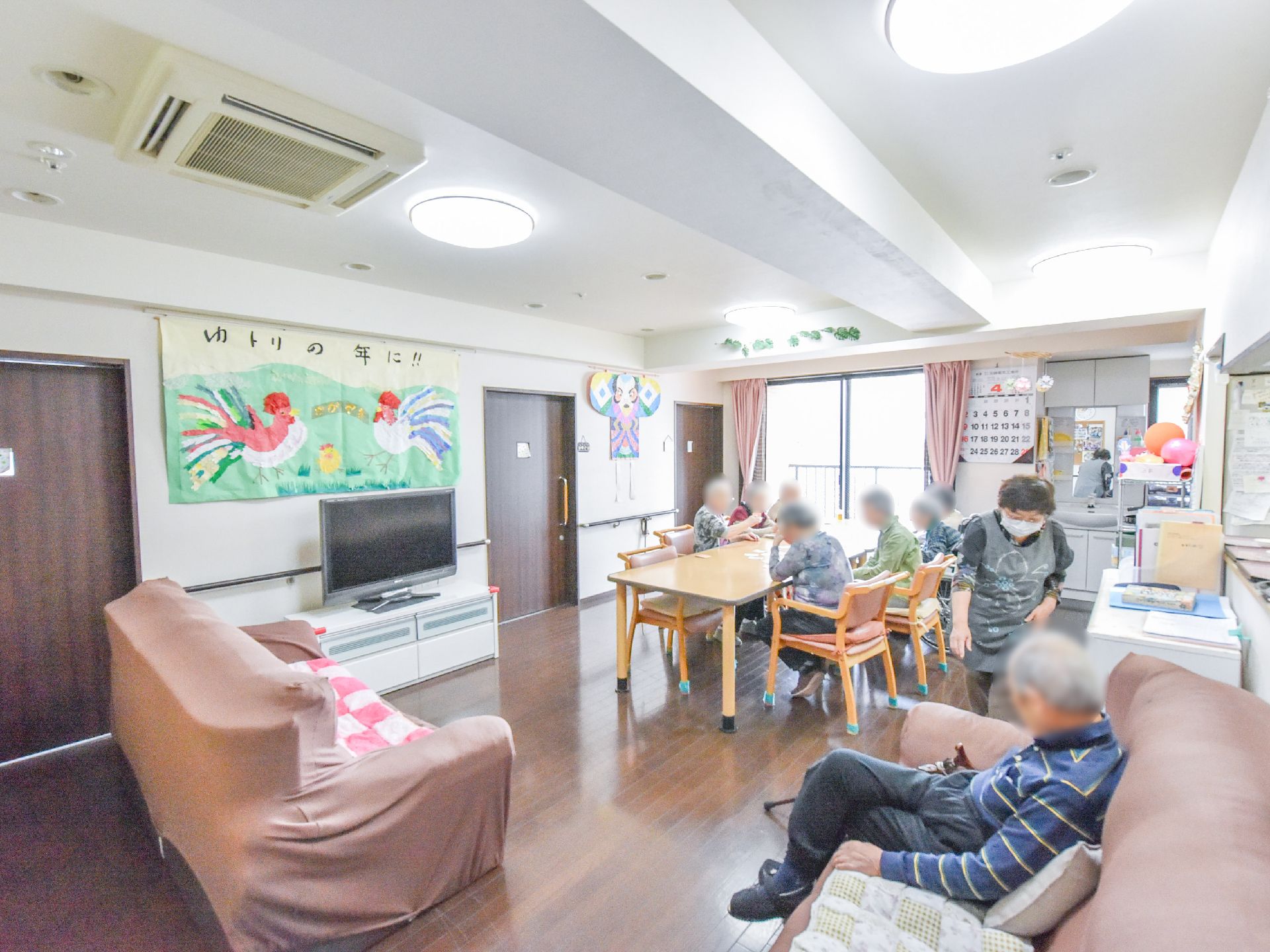 ダイニングの壁や天井には、居住者達が手作りした作品が飾られている。ダイニングには居住者達が集まり、スタッフも一緒に過ごしている。