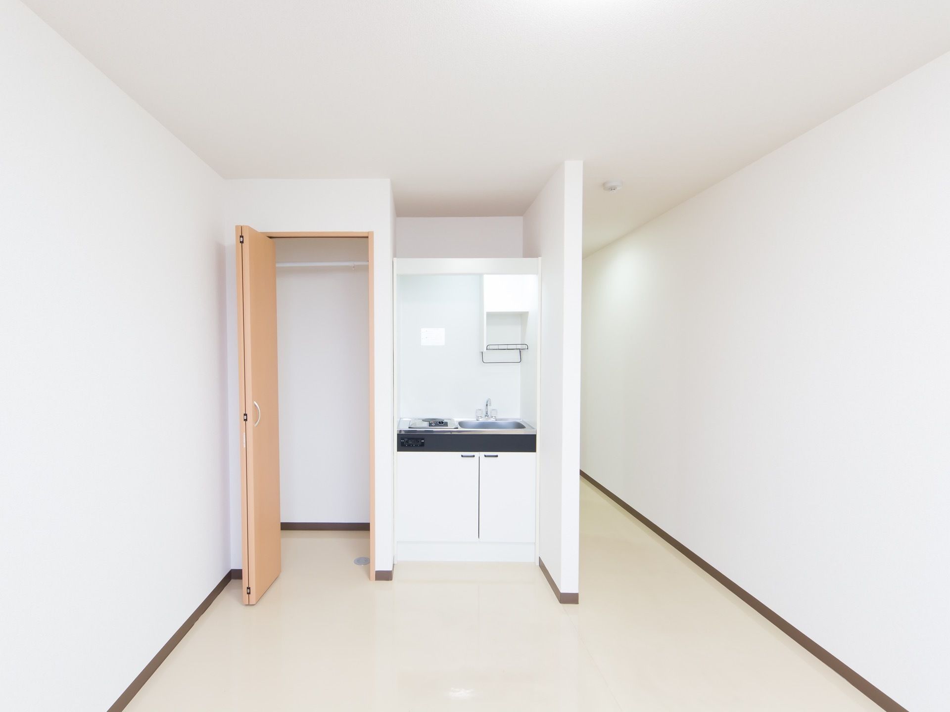 居室にはクローゼットが備えつけられており、ハンガーポールが取りつけられている。横にはミニキッチンが設置されている。