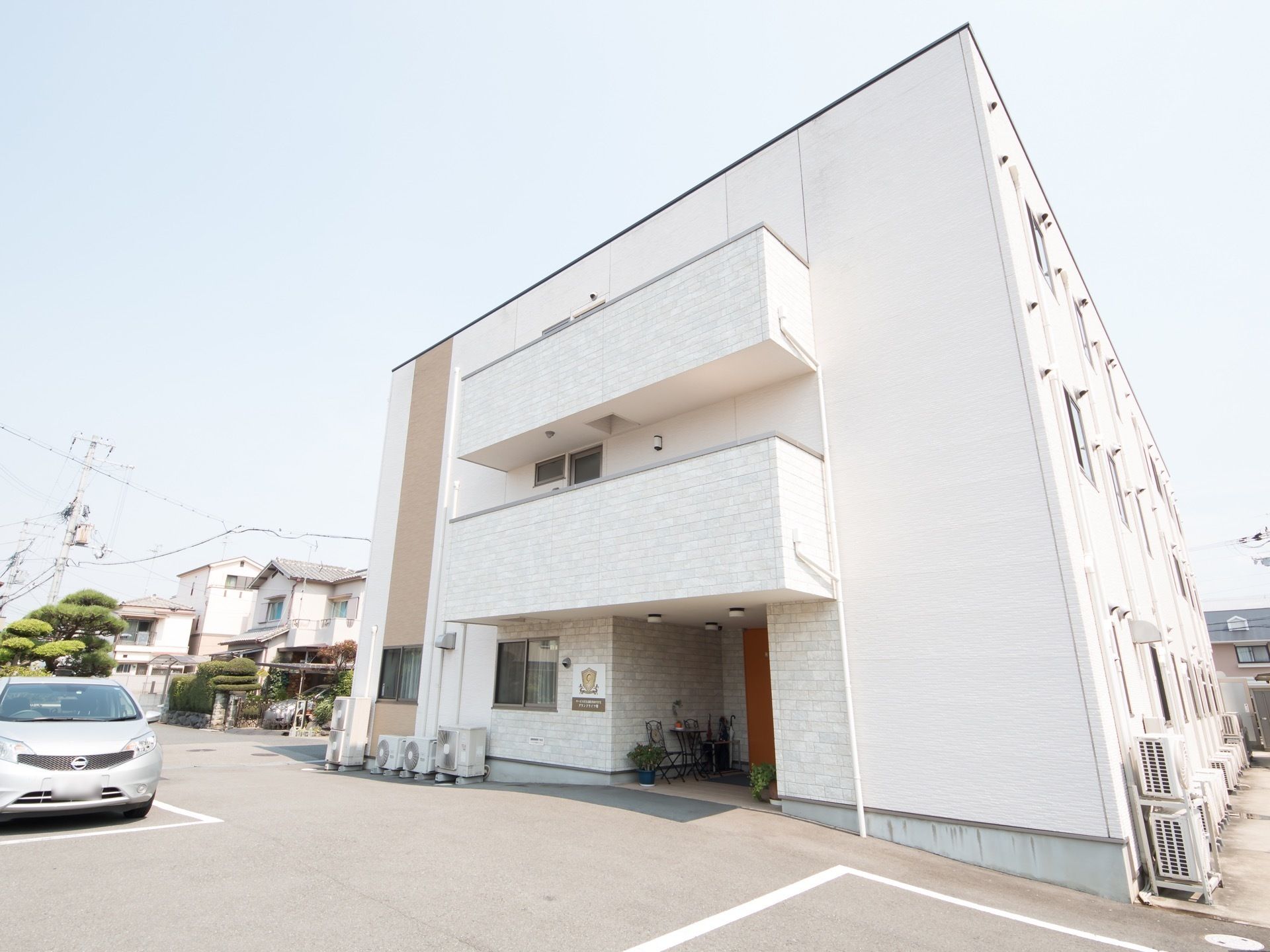 木造３階建ての白い建物である。玄関は中央部分にあり、建物の前は駐車場となっている。玄関に笠立が置かれている。