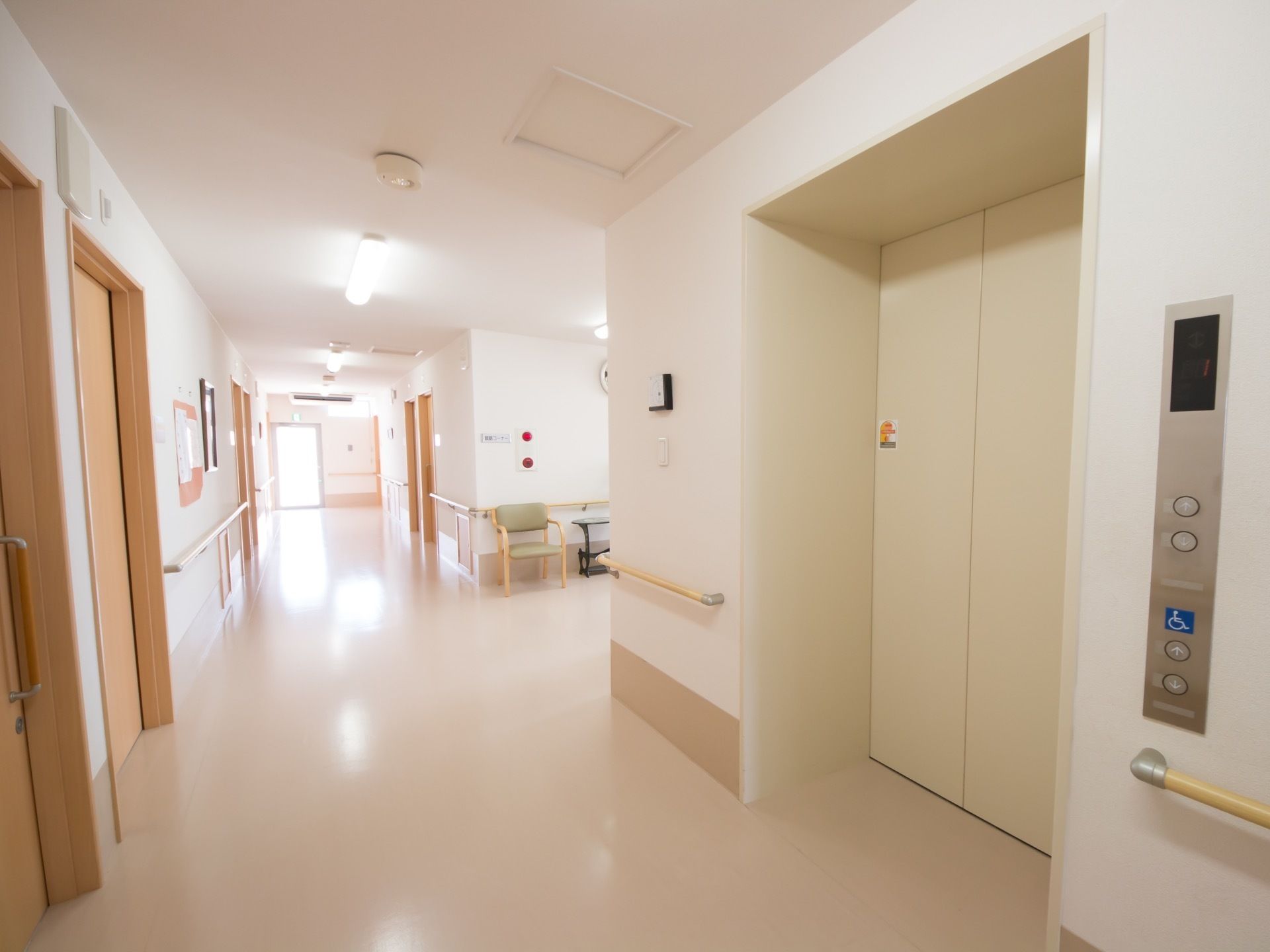 横幅の広い廊下である。通路沿いに手すりが取りつけられている。木造３階建ての建物でエレベーターが設置されている。