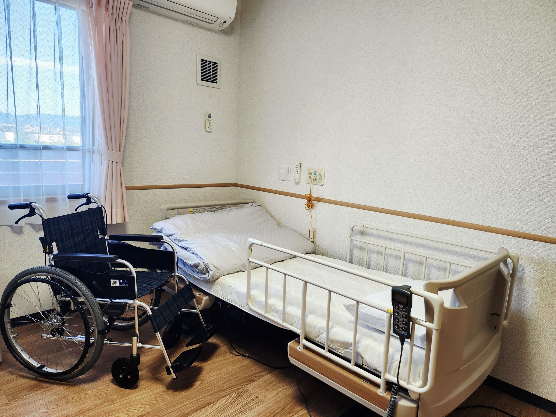 ベッドなどの家具が置かれていない状態の居室。エアコンやナースコールが取りつけられている。窓は大きく、室内を明るく照らしている。