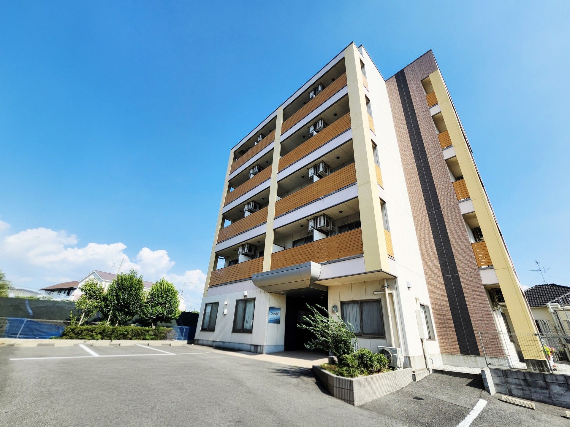 施設は建物横に駐車場を完備しており、施設入口への移動がスムーズに行われる。シルバーとブルー色の乗用車が2台停車している。