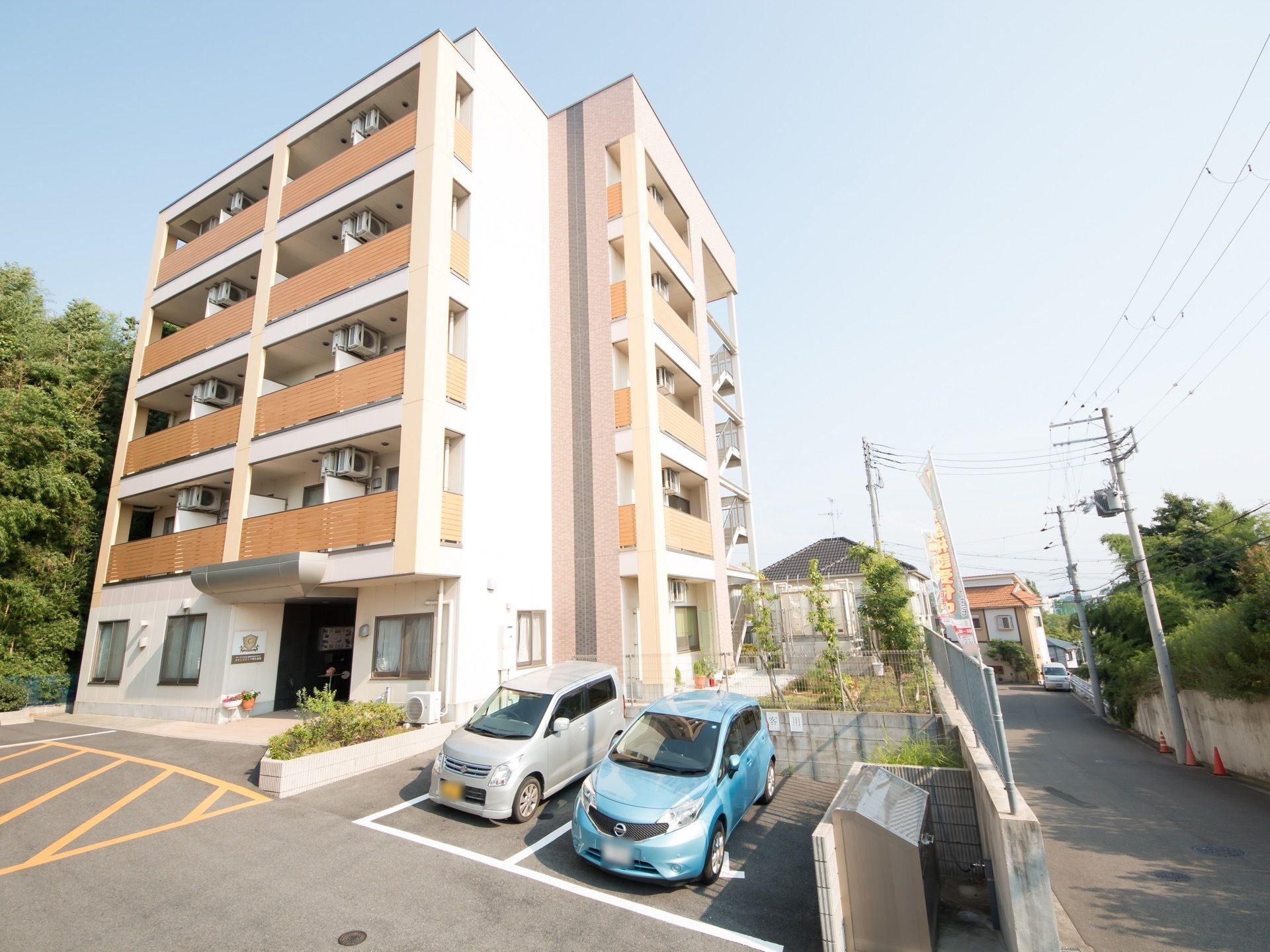 施設は建物横に駐車場を完備しており、施設入口への移動がスムーズに行われる。シルバーとブルー色の乗用車が２台停車している。