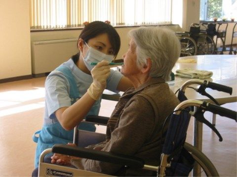 車椅子をご利用の女性の方の口腔内をチェックする女性の歯科衛生士
