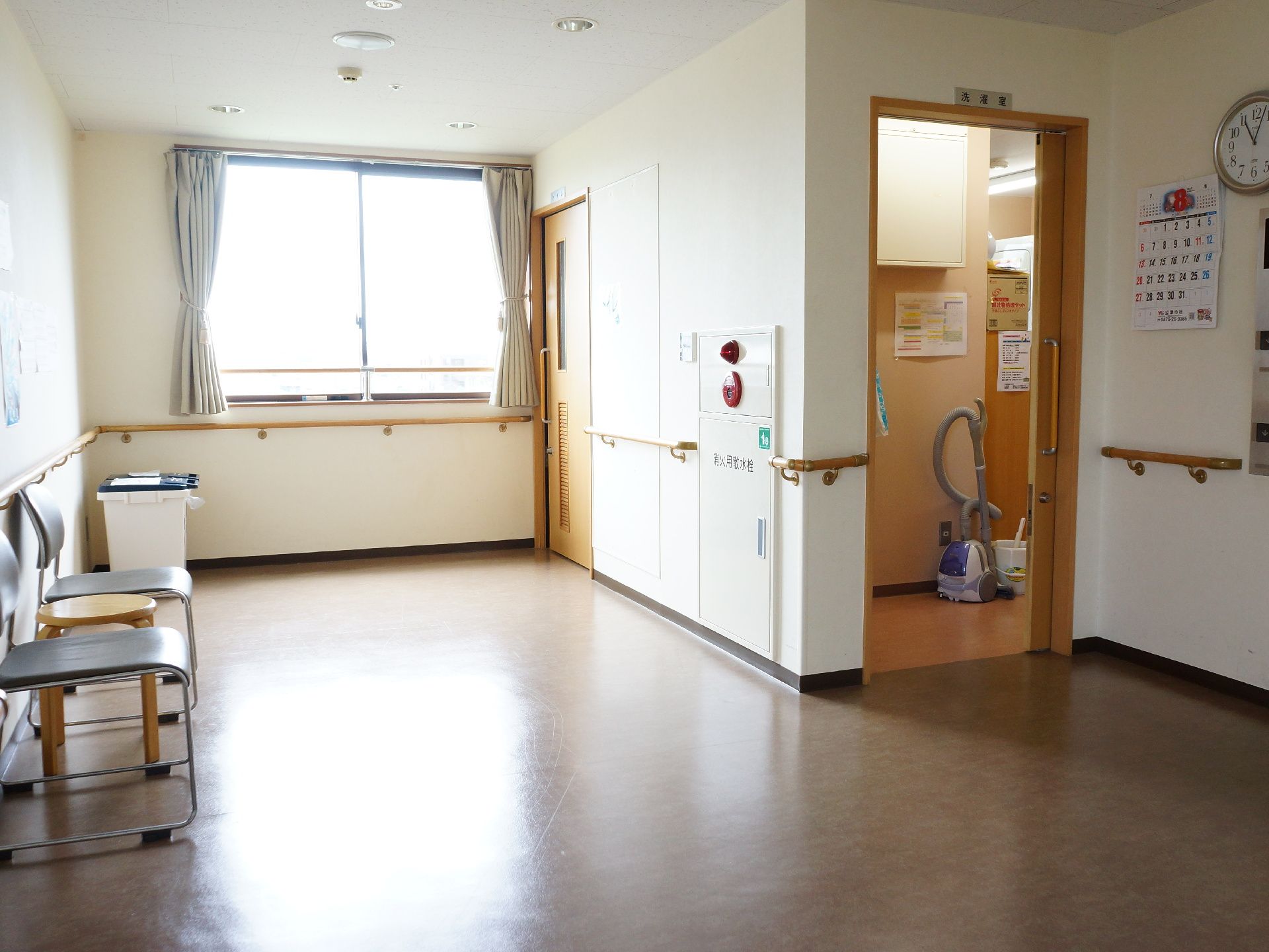 エレベーターホールは広々とした空間になっている。壁際には複数椅子が置かれている。洗濯室が隣接している。