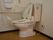 洋式トイレには温水洗浄便座が設置されている。横の壁にはL字の手すりとスタッフの呼び出しベルが付いている。