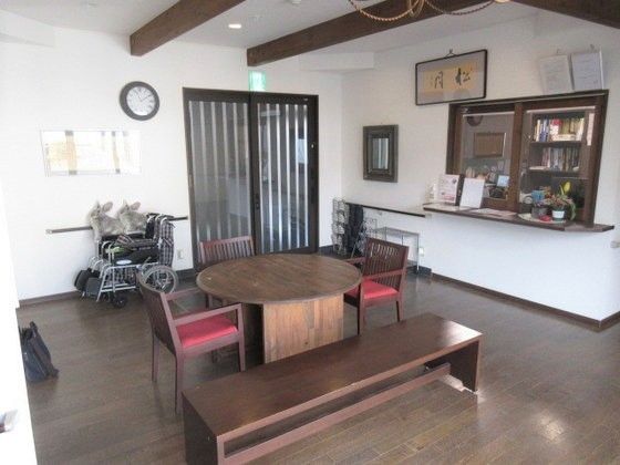 非常口誘導灯が上部に設置された扉横に車椅子が畳まれて置かれているロビー