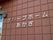 赤い外壁の建物で、ドアの右側に施設名が大きく書かれている。ドアには掲示物が貼られている。ドアと施設名の間にライトが取り付けられている。