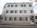 施設は1階部分の壁がピンク色で、2階と3階部分の壁が白色となっている。左側の角には、白いクリニックの看板が設置されている。