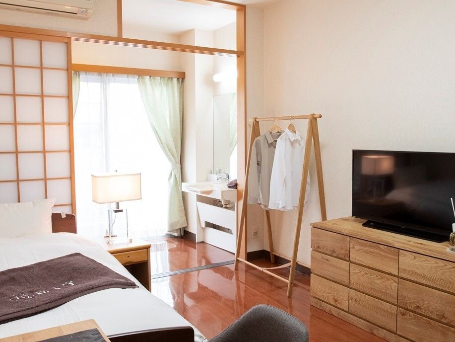 家具やインテリアがたくさん置かれた家庭感あふれる部屋。天井にシンプルな照明、床にはカーペットが敷かれている。