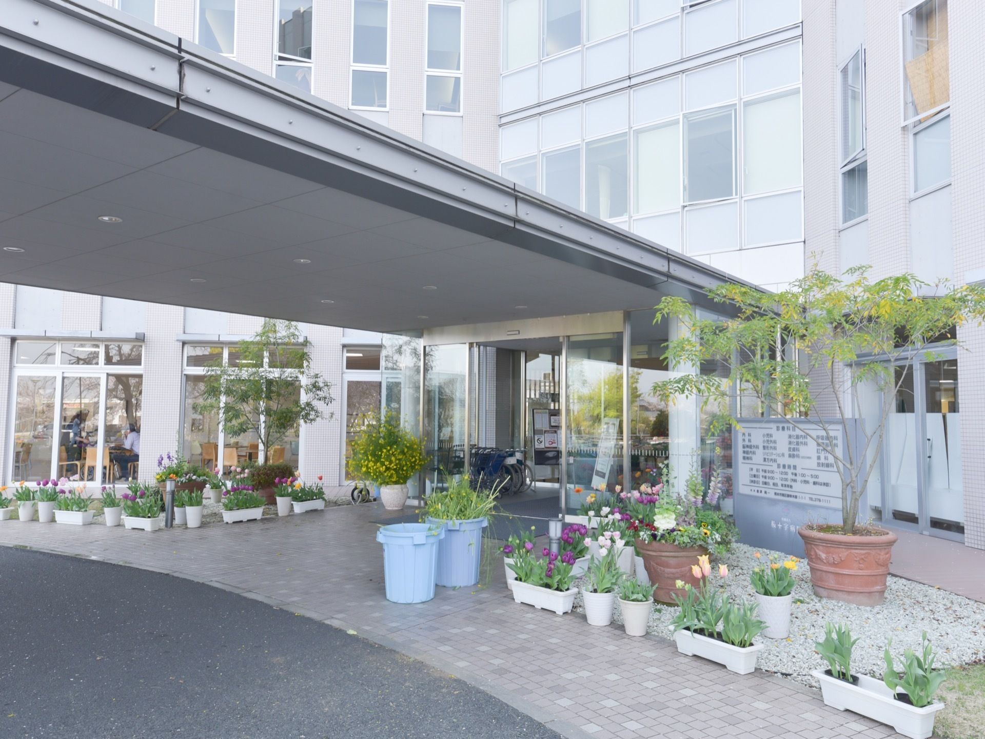 玄関の入り口前には車寄せがあり、大きなひさしが付いている。たくさんの植木鉢が置かれており、入り口に向かって右側に施設の看板が設置されている。