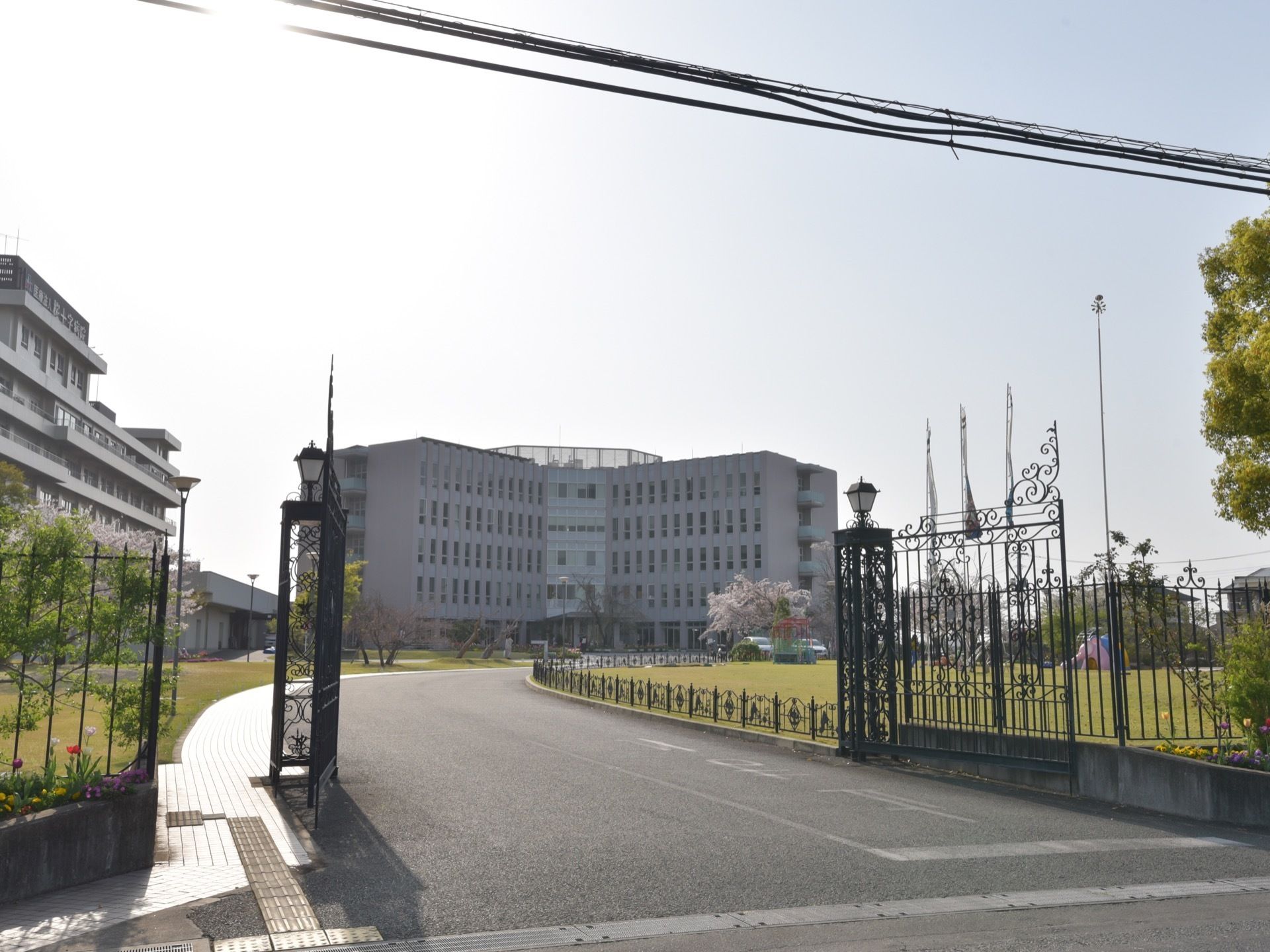 施設の敷地入り口から見た外観である。黒いアイアンの門を入ると、整備された芝生の庭になっており、建物までは車道が続いている。