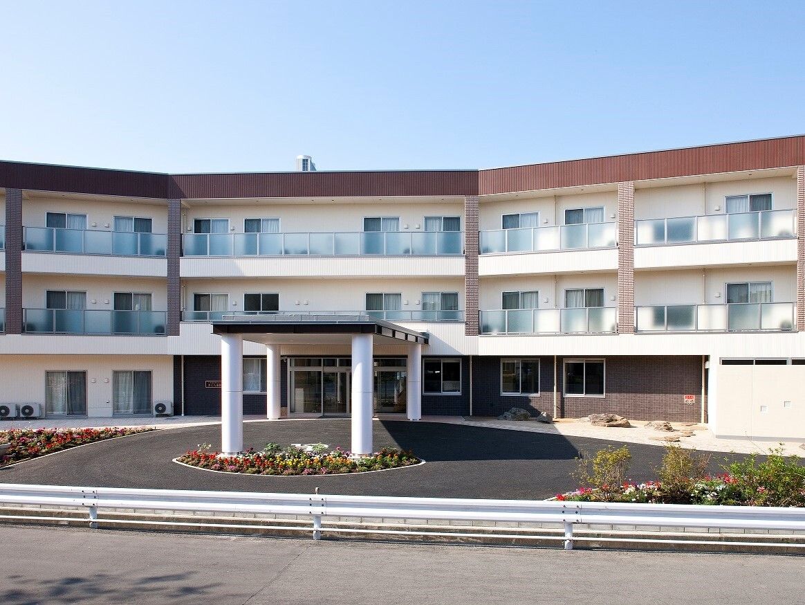 入口横に喫煙所が設置してあり、椅子が２脚配置してある。入口前まで車寄せがあり、屋根があるため濡れずにご入館が可能である。