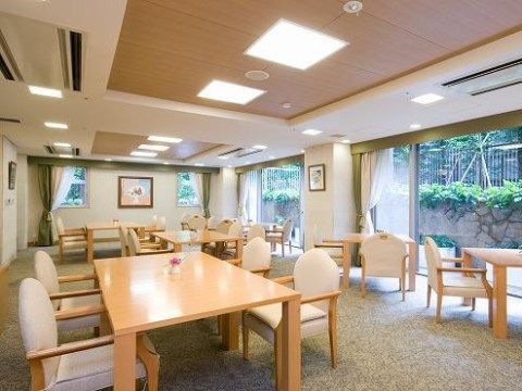 広々とした空間に絨毯や木の色合いの家具を配置している。入居者様には、リラックスしてお食事をお楽しみいただける。