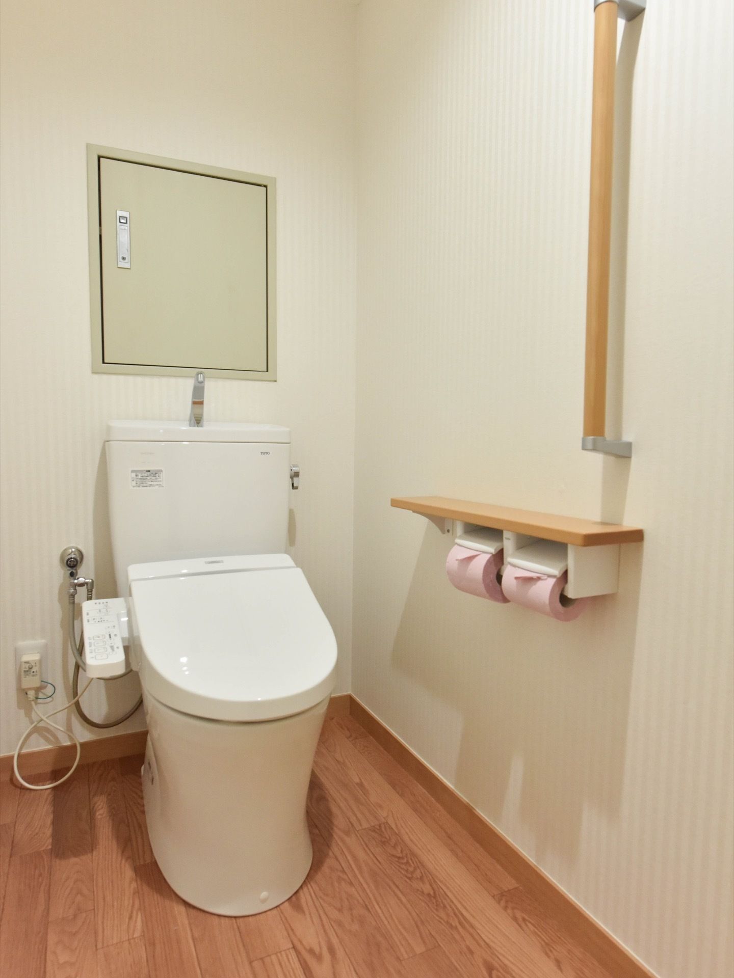 居室にトイレが完備されている。便座は温水の洗浄機能が付いている。壁に手すりが付いていて、立ち座りをサポートしてくれる。