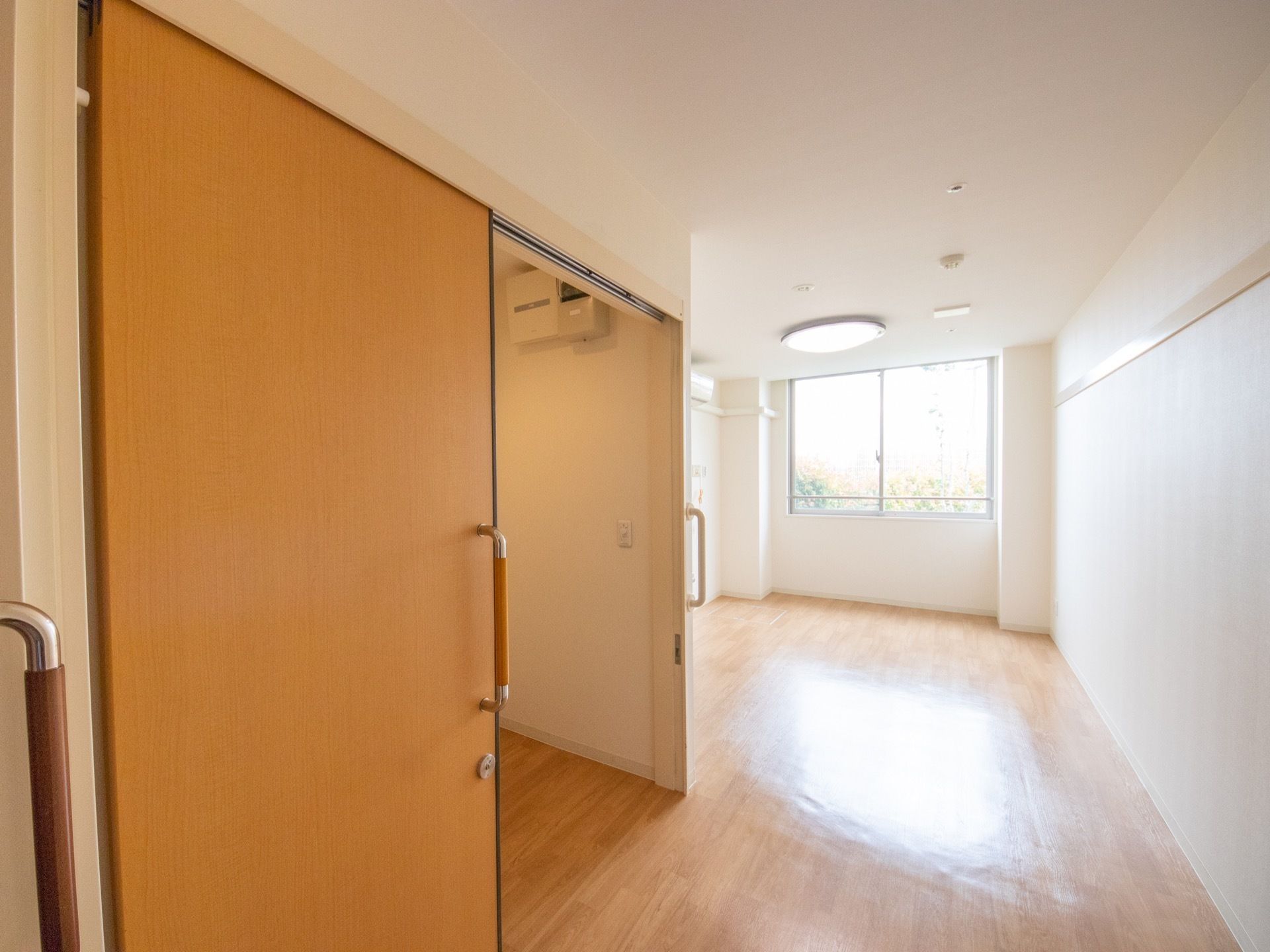 大きな窓から入る外光は入口まで届く。居室へ入るとすぐ左手にトイレがあり、室内とトイレはバリアフリー化されており段差が無い。