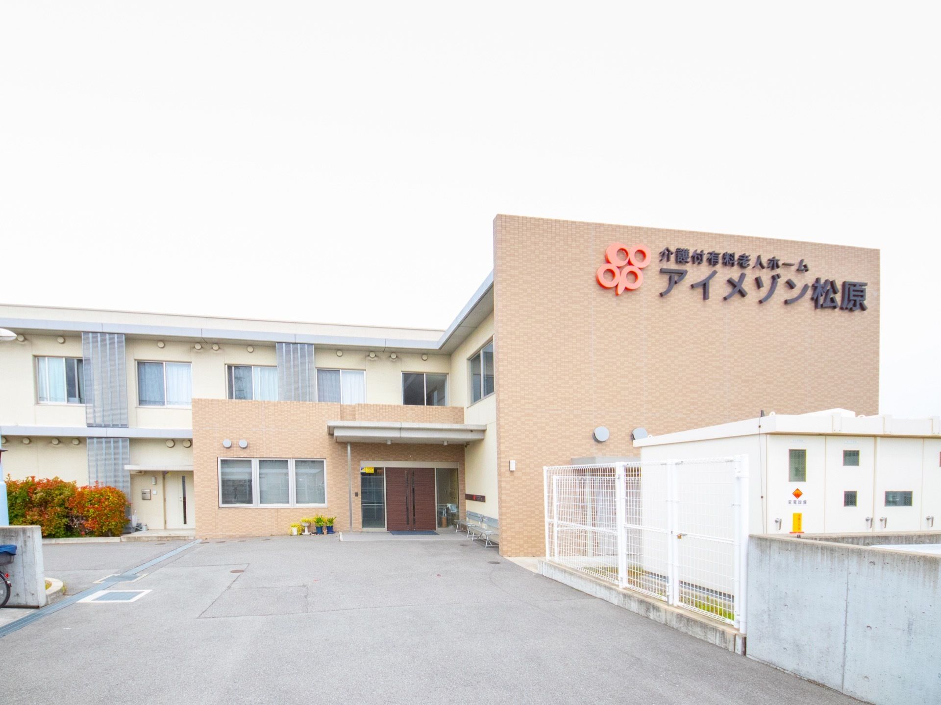 建物の最上部には大きく施設名が表示されている。玄関ポーチには屋根があり、玄関前は車も入れるスペースが大きく確保されている。