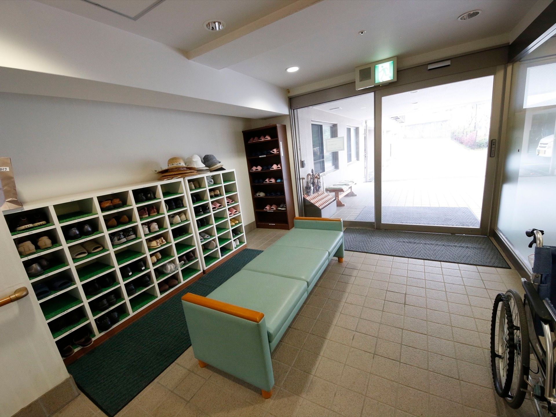 玄関の外には傘立てが設けられている。下駄箱が設置されており、いくつもの靴が収納されている。下駄箱の上には帽子が重ねて置かれている。